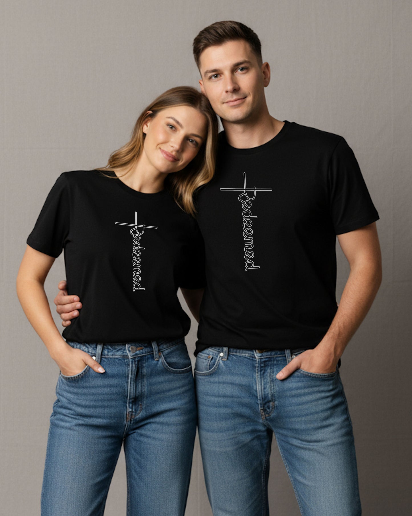 A woman and a man wearing black t-shirts with an elaborate white Heavenly Dreamwear designed 'Redeemed' logo printed on the front.