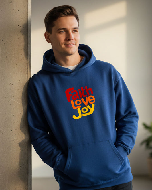 Man standing indoors wearing a blue hoodie with a red, orange and yellow Heavenly Dreamwear text logo printed on the front.