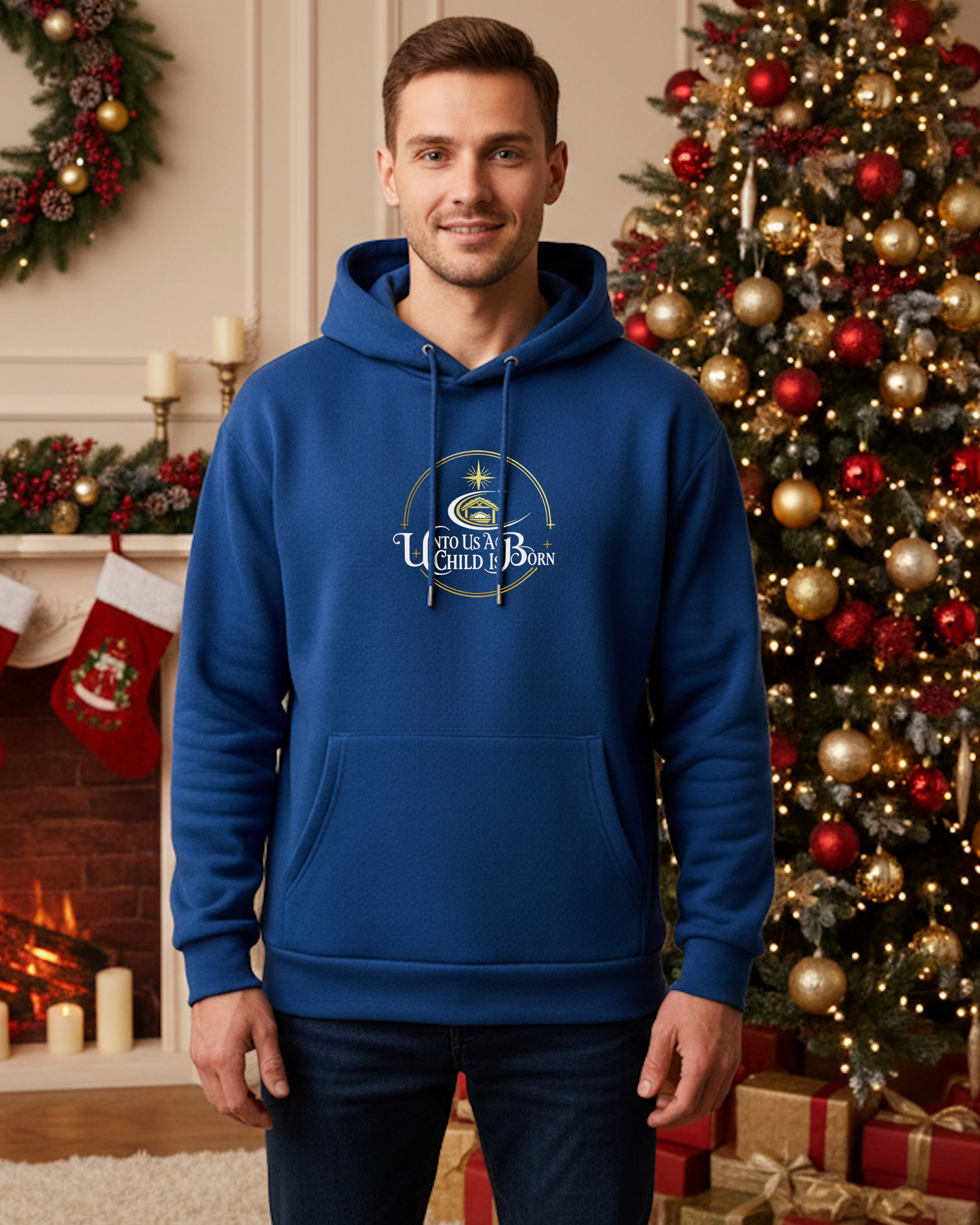 A man wearing a blue hoodie that has the white text, "Unto Us A Child Is Born" within a gold logo, in Christmas decorated room with a fireplace.