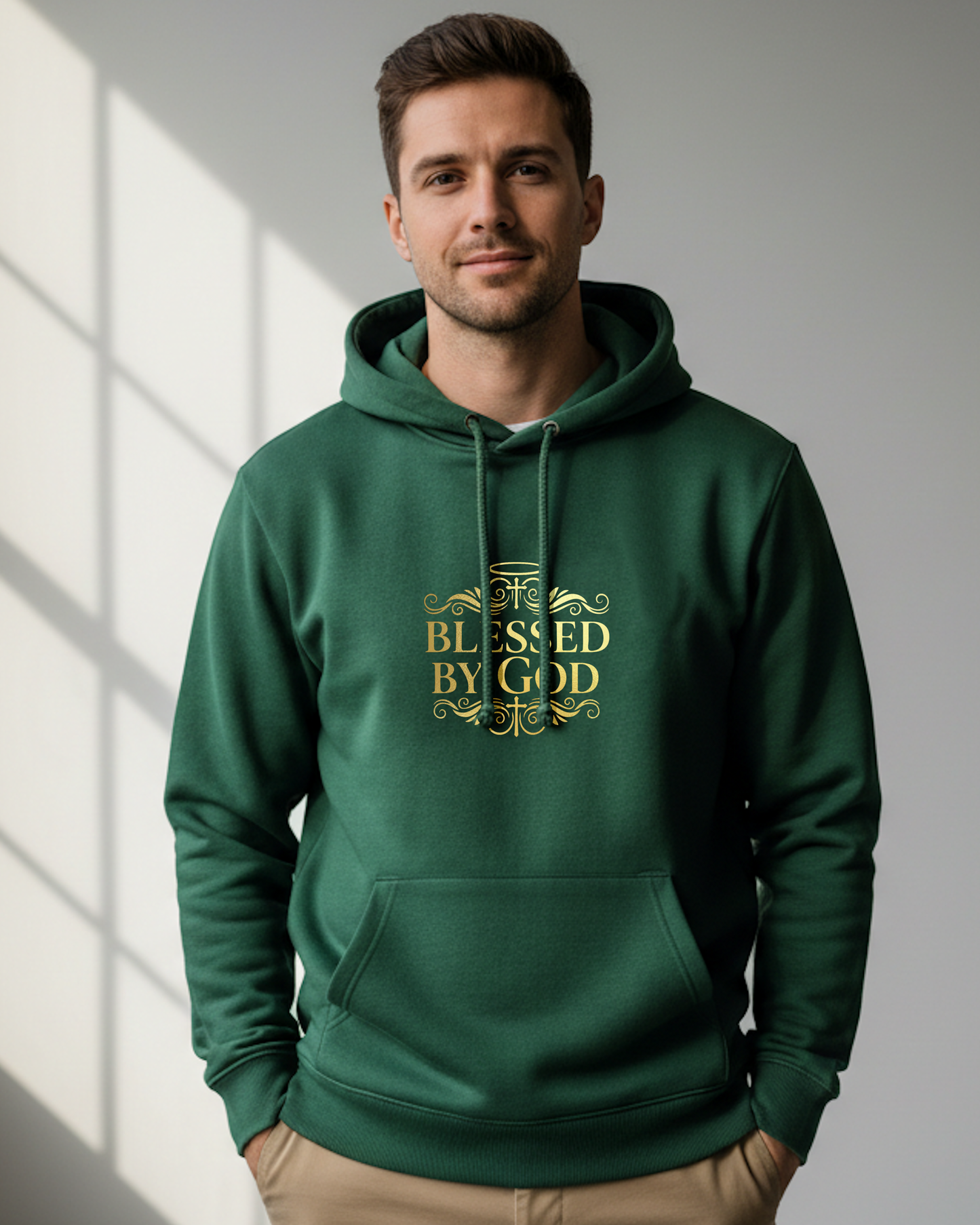Man wearing a green hoodie with 'Blessed by God' gold text, standing in a well-lit room.
