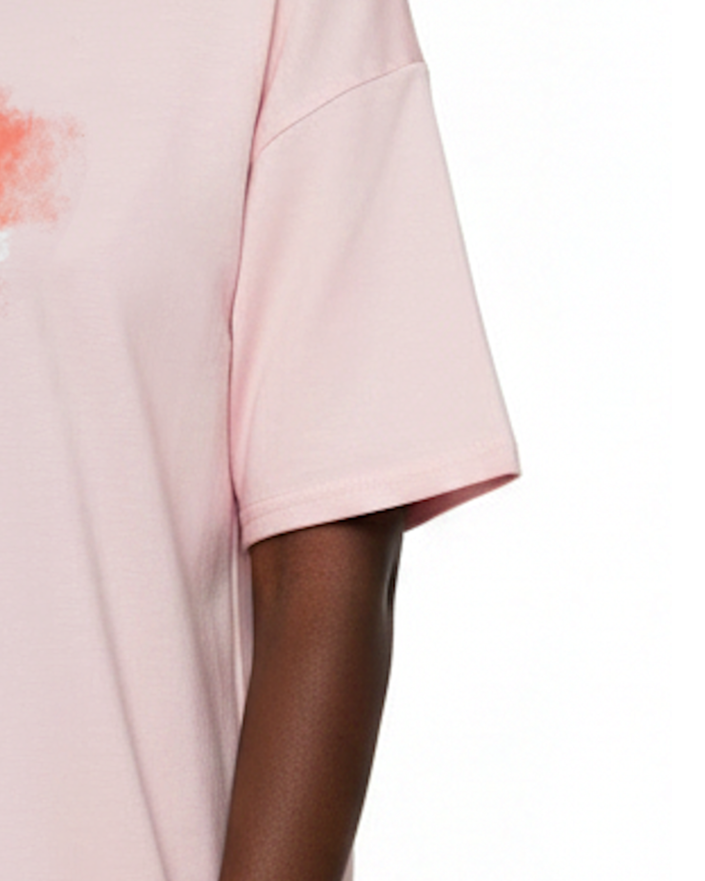Closeup of the sleeve of a light pink t-shirt dress against a white background