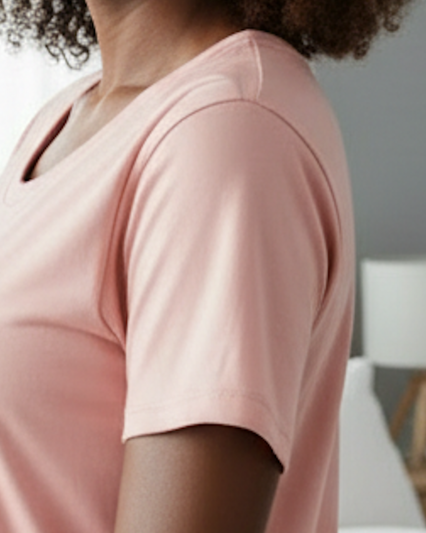 Closeup of the sleeve a light pink t-shirt dress worn by a woman