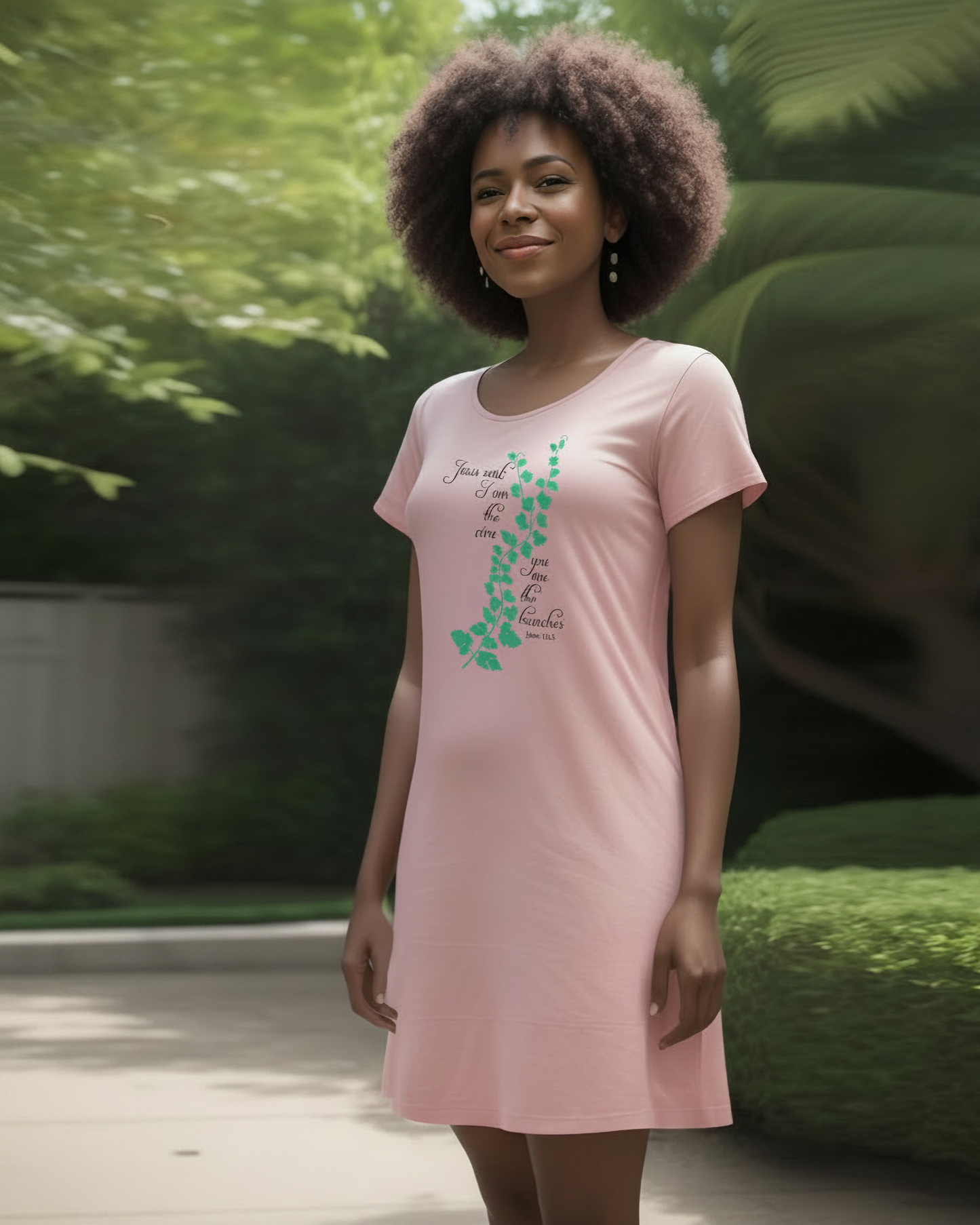 A woman wearing a pink t-shirt dress with an elaborate green vine branch with the text, "Jesus said: I am the vine you are the branches" printed in black text on either side.