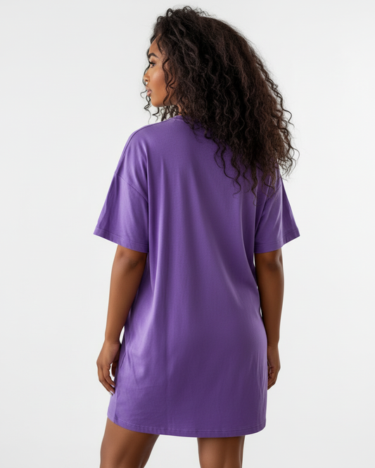 Rear view of a woman wearing a purple t-shirt dress against a white background.