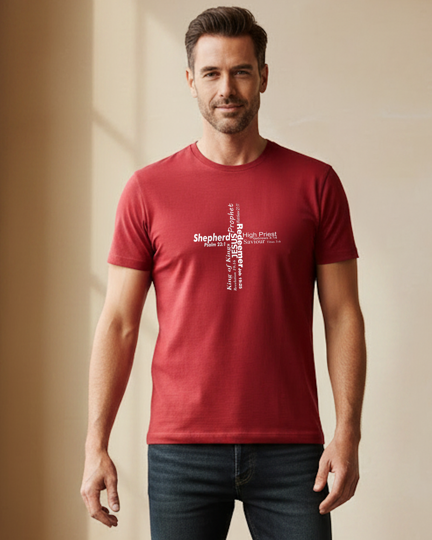 A man wearing a red short-sleeve crewneck t-shirt against a beige wall. The front of the shirt features a white typographic cross design with the various roles of Jesus.