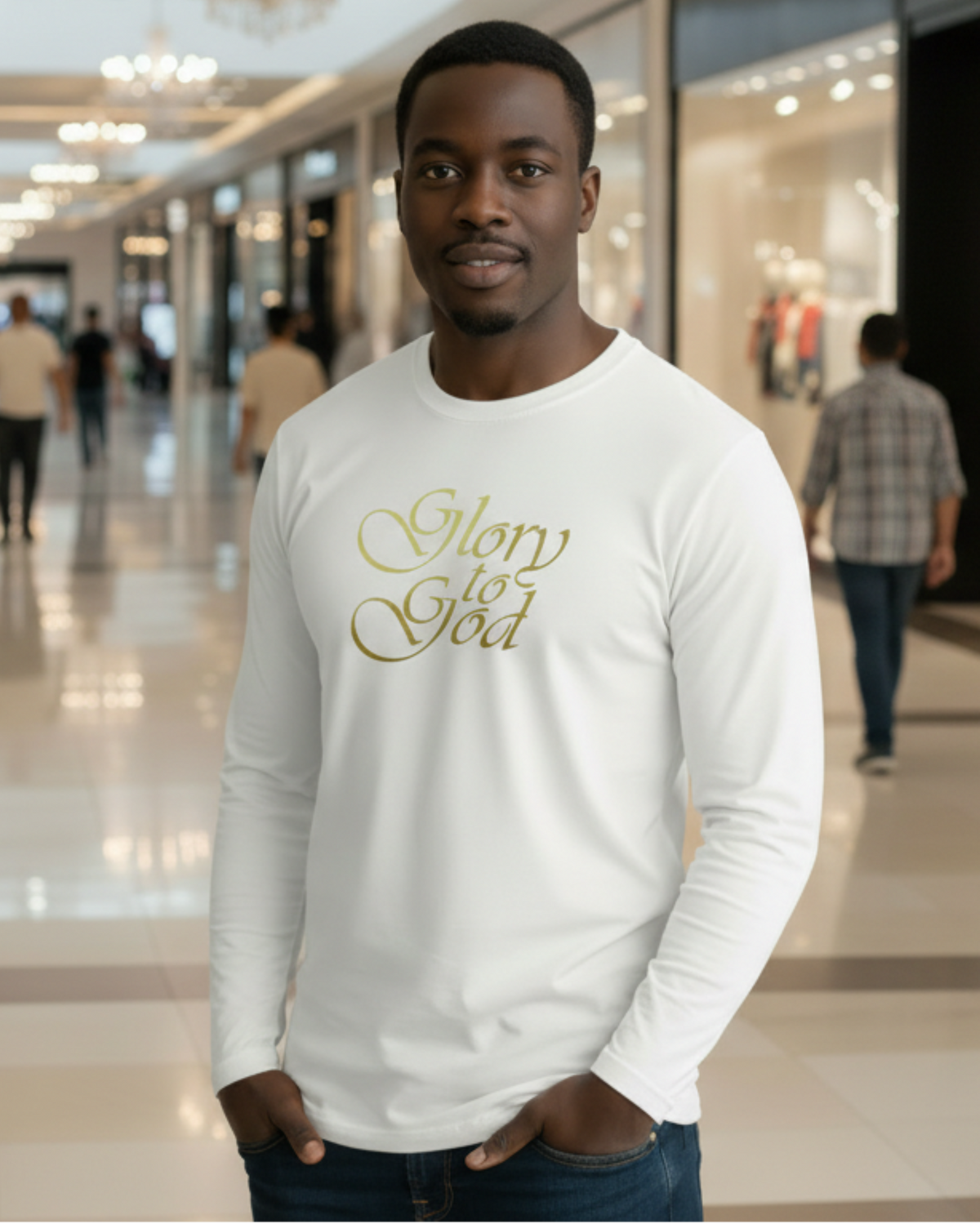 A man wearing a white long-sleeve t-shirt with 'Glory to God' printed in gold cursive text on the chest, standing in a brightly lit, blurred shopping mall corridor.