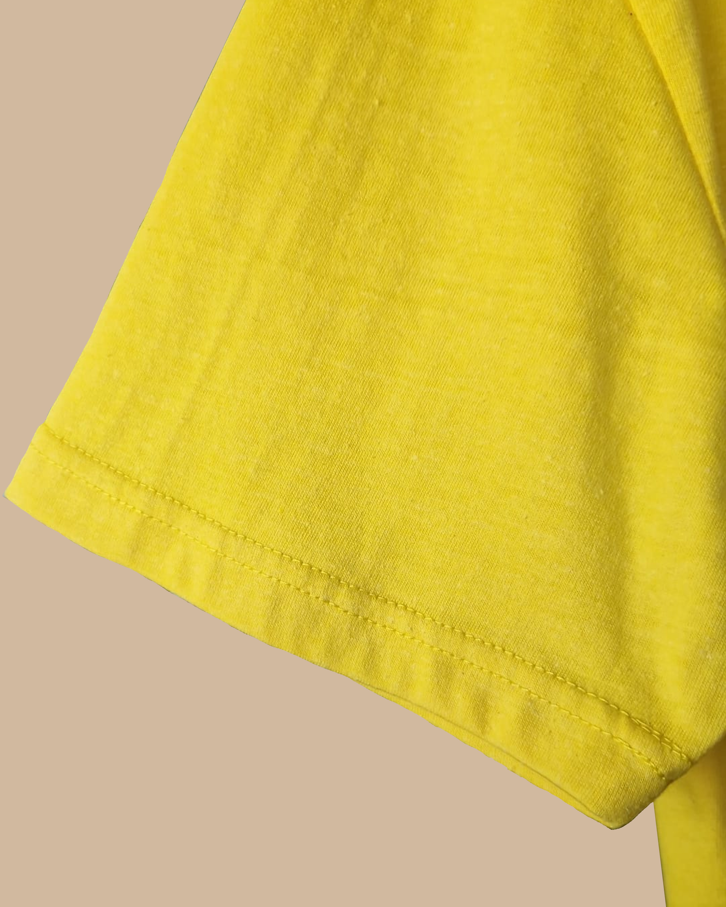 Close-up of a bright yellow fabric sleeve or garment corner with visible stitching, set against a plain beige background.