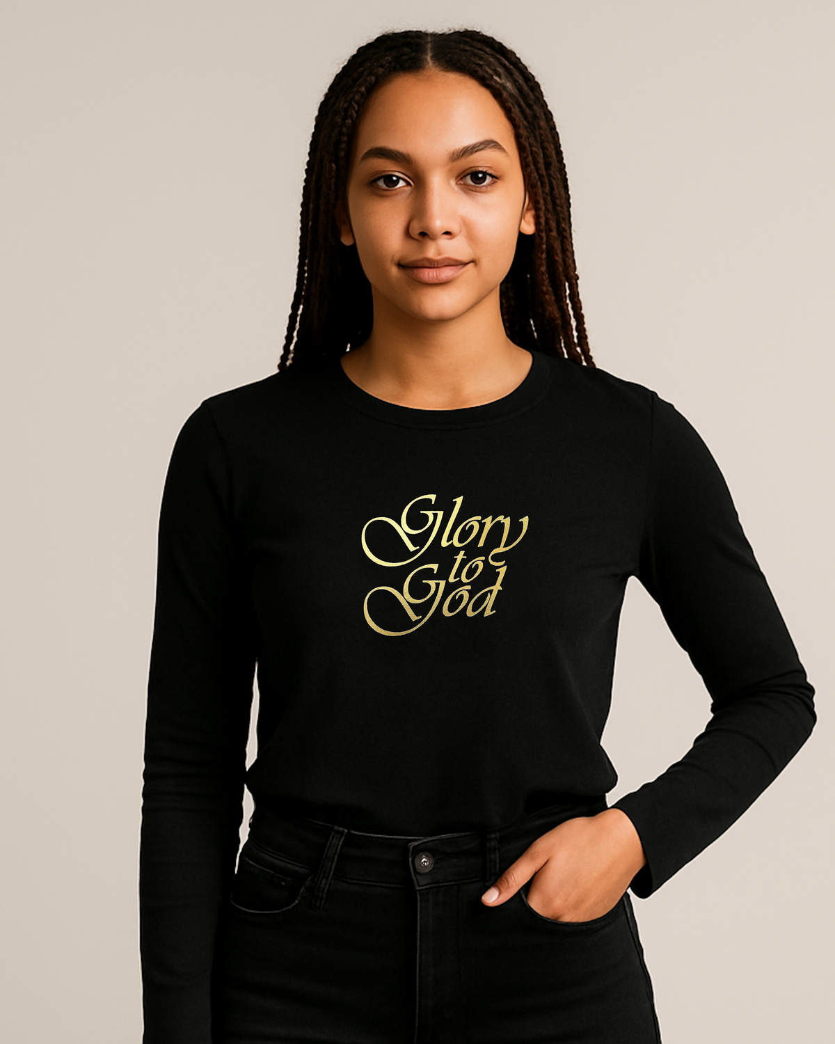A woman with braided hair wearing a black long-sleeve crewneck shirt with 'Glory to God' printed in gold cursive text on the chest, paired with black jeans, against a solid light gray background.