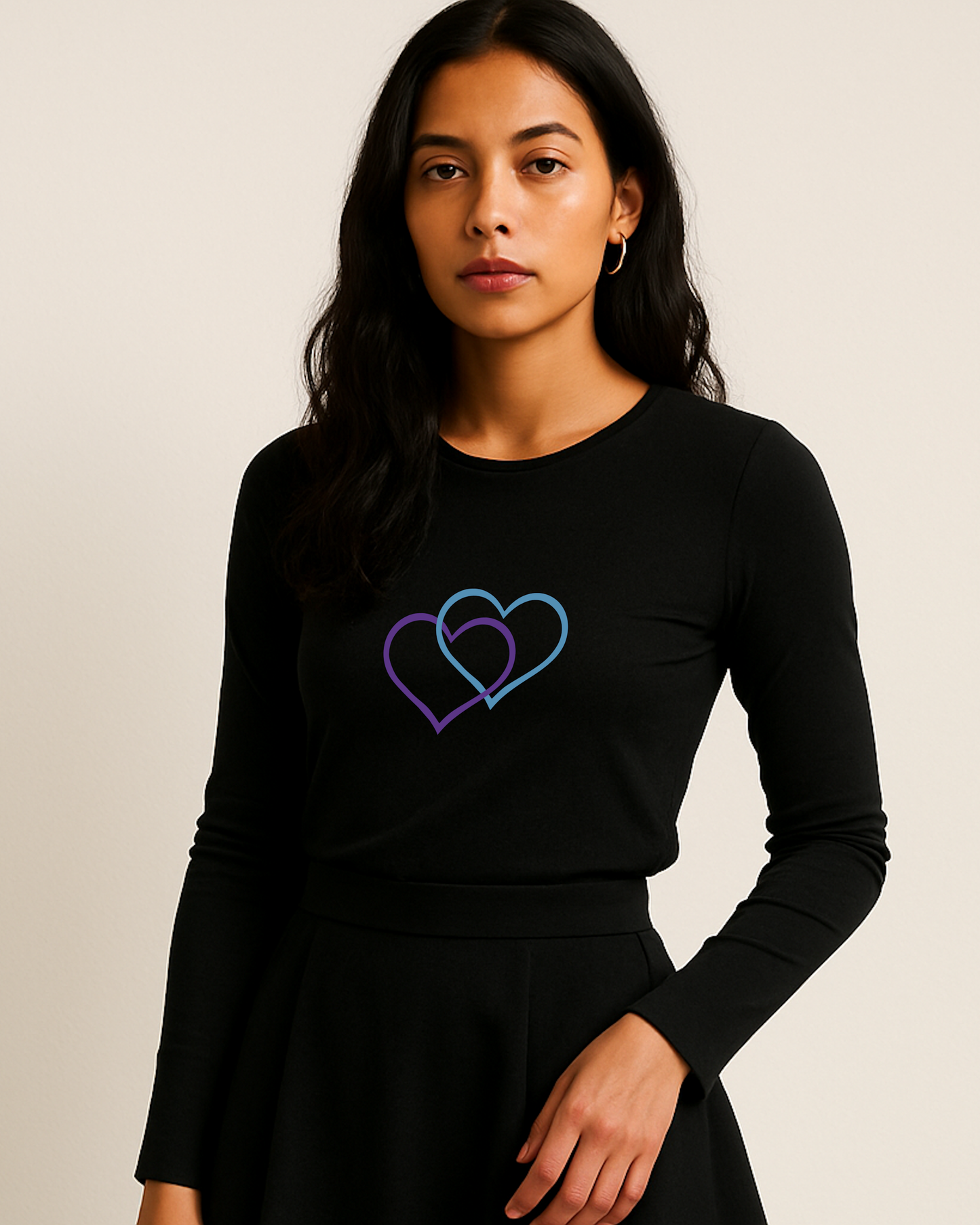A woman wearing a black long-sleeve shirt with a colorful inter-twinned dual purple/blue heart design on a plain background