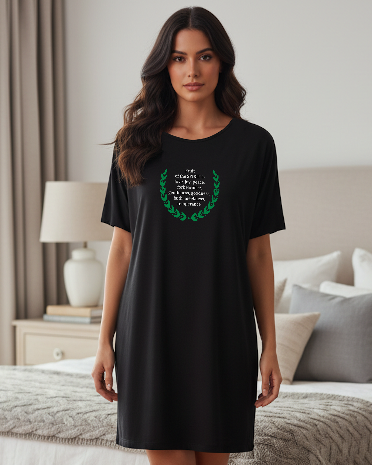 Woman wearing a black t-shirt dress with a green design and white text in a bedroom setting