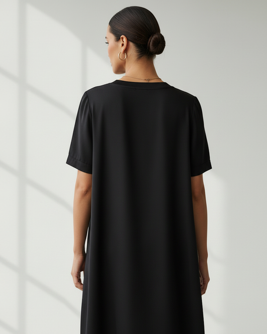 Rear view of a woman in a bright room wearing a black t-shirt dress.