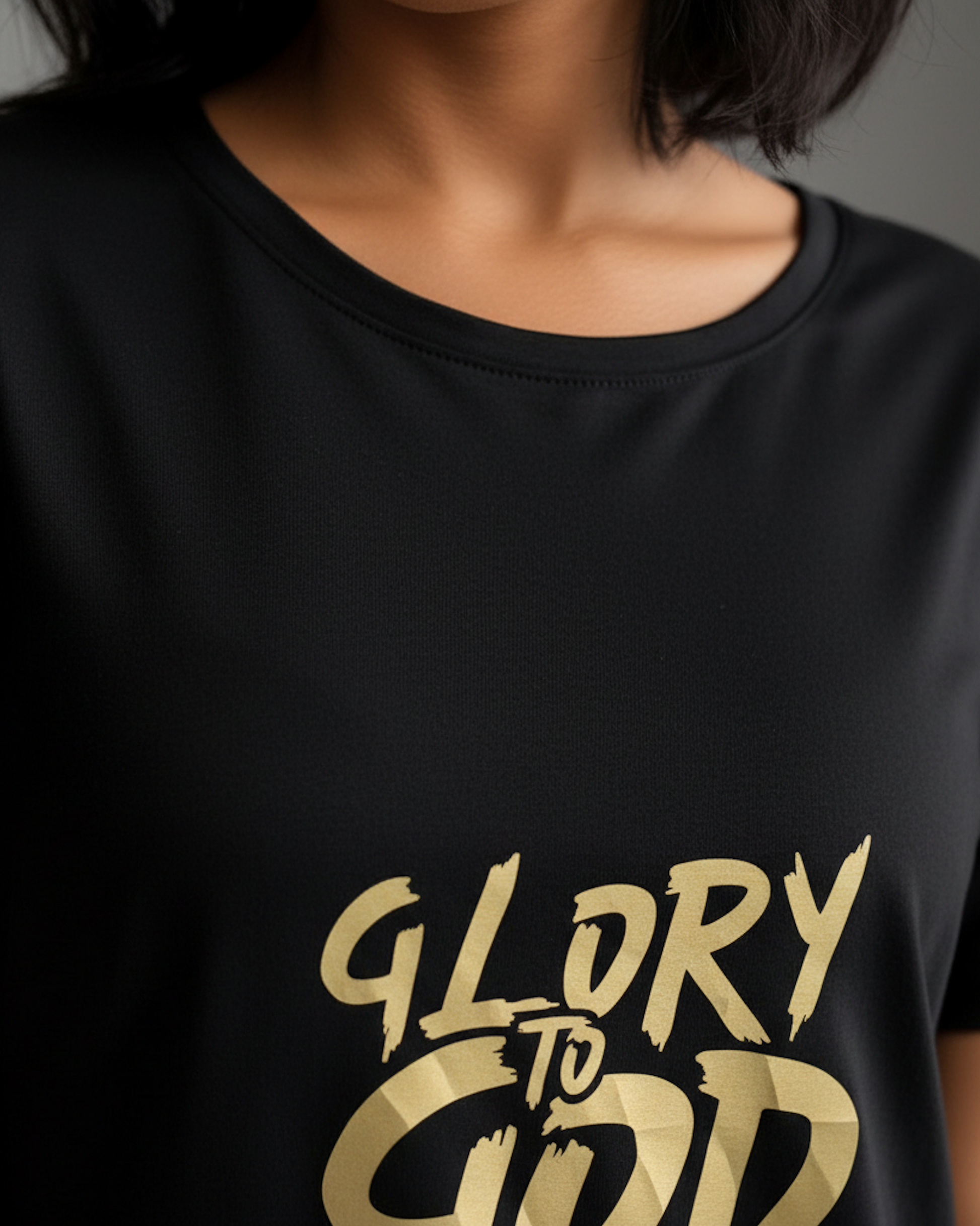 View of neck of  woman wearing a black t-shirt dress with a gold logo.