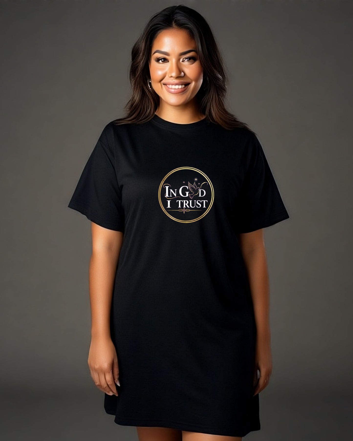 Woman wearing a black t-shirt dress with a logo bearing text, "In God I trust" on a gray background.