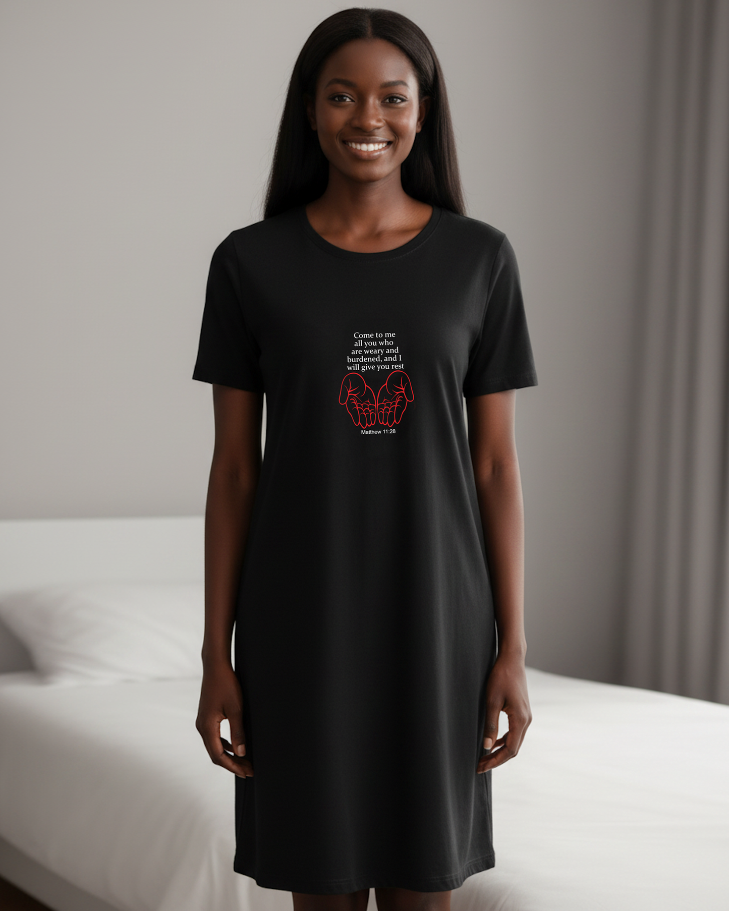 A woman wearing a black short-sleeve t-tshirt dress with a red and white graphic print on the front, standing in a bedroom setting.