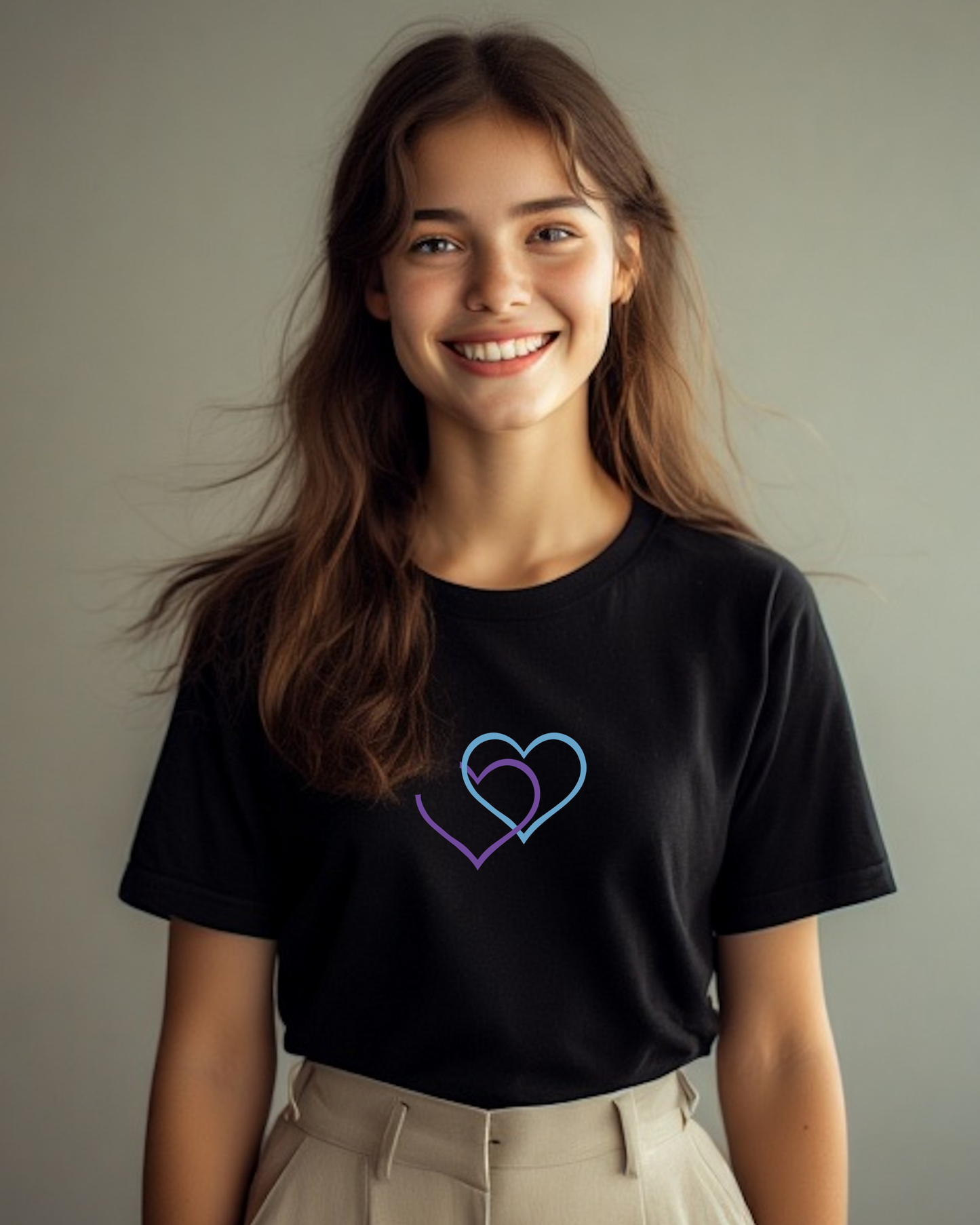 A woman wearing a black t-shirt with a Heavenly Dreamwear logo comprised of an purple and blue inter-twinned hearts.
