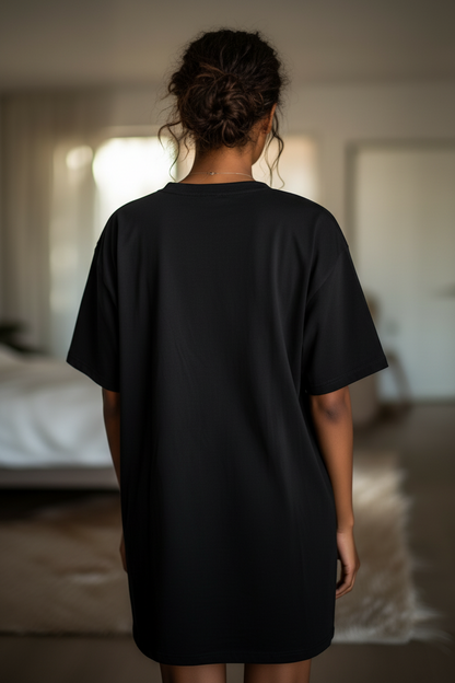 Woman wearing a black t-shirt dress in a bedroom setting
