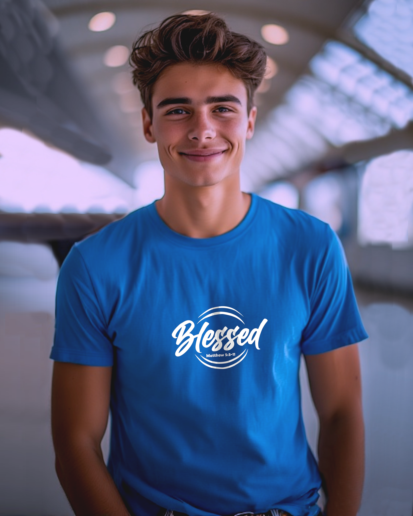 A young man wearing a blue t-shirt with a white text logo that says 'Blessed' t-shirt in an airport.