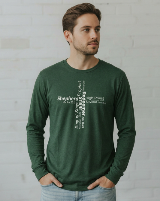 A man wearing a dark green long-sleeve t-shirt against a plain light gray wall. The front of the shirt features a vertical white text graphic reading 'Shepherd of Kings, Prophets, High Priest, Jesus' with biblical references.