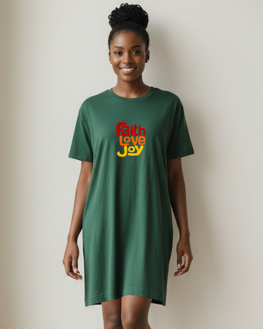 Woman wearing a dark green t-shirt dress with 'Faith Love Joy' text against a beige wall.