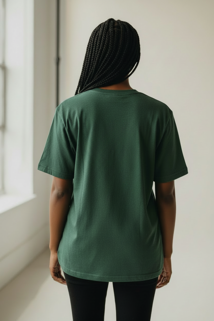 Person wearing a green t-shirt standing in a room with a window.