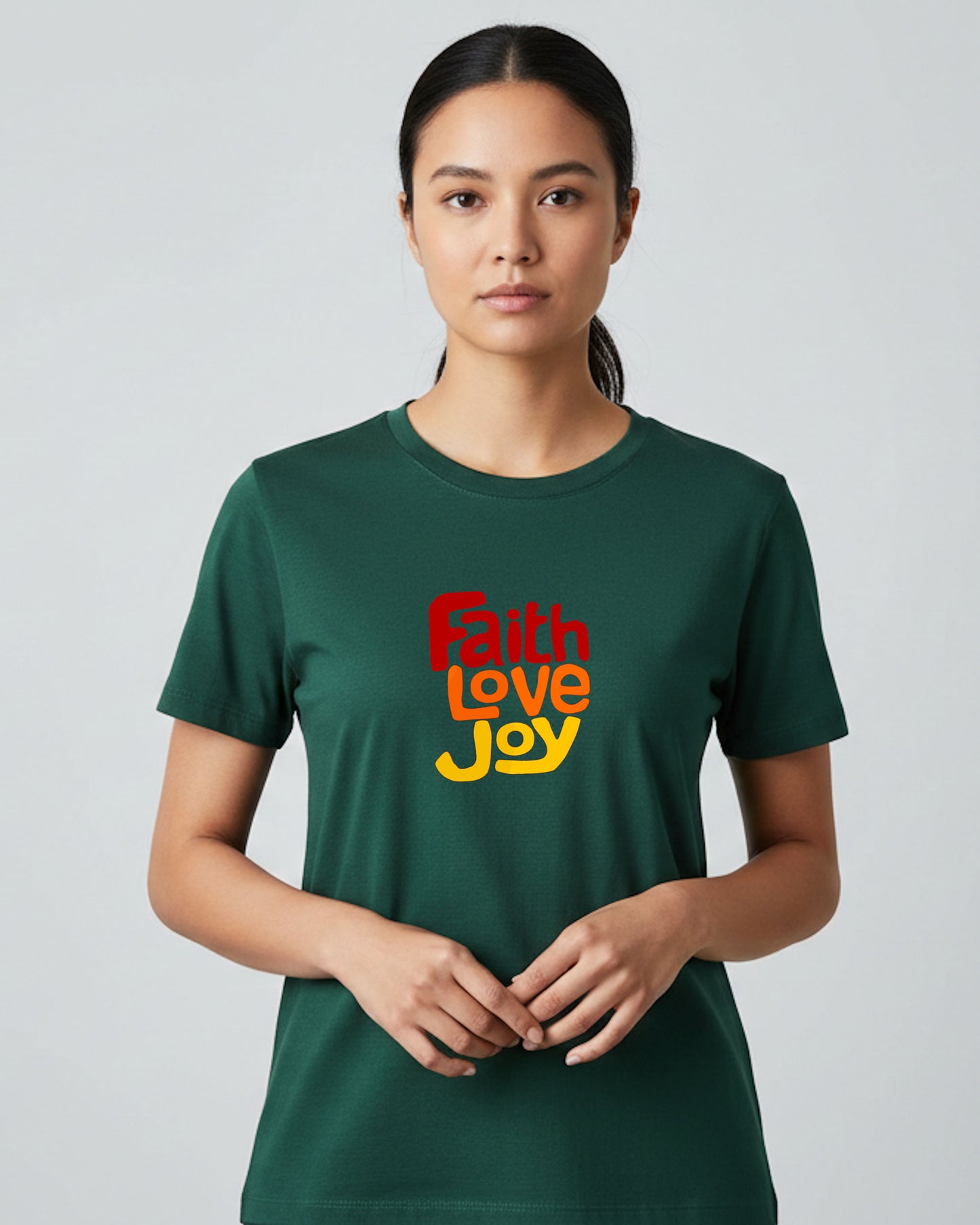 Woman wearing a dark green t-shirt with 'Faith Love Joy' text on a plain background