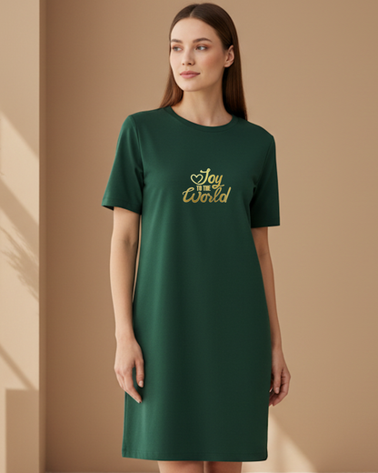 Woman wearing a green t-shirt dress with 'Joy to the world' text logo on a beige background