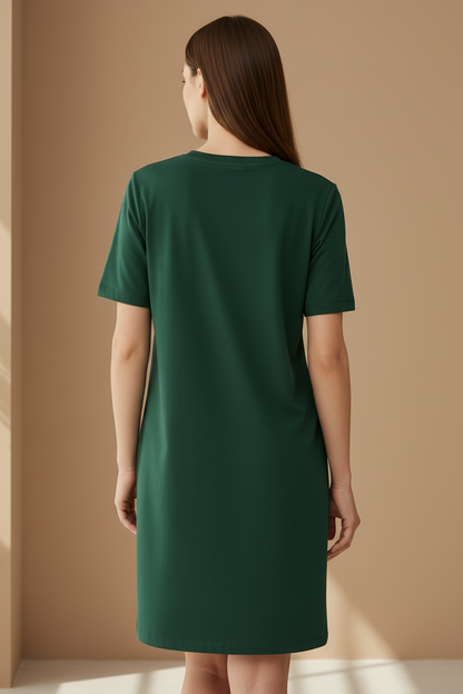 Woman wearing a dark green t-shirt dress against a beige wall