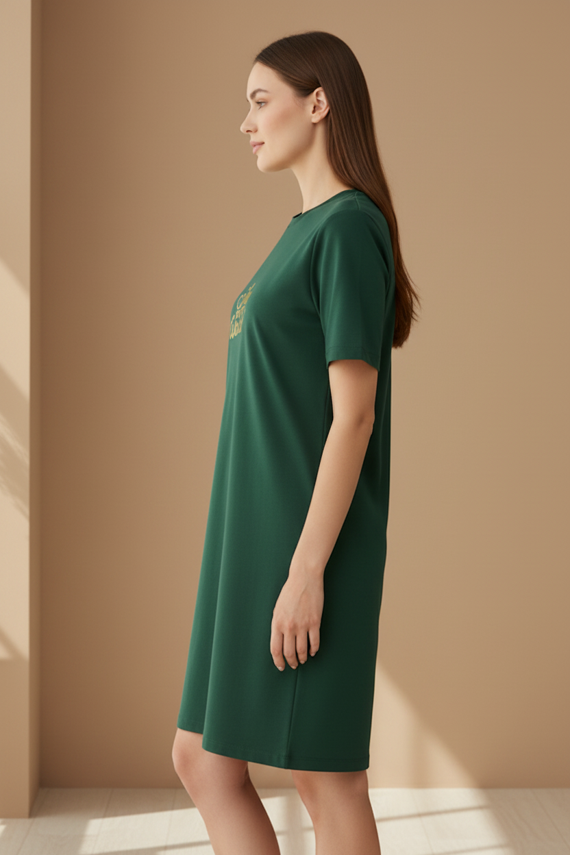 Woman wearing a dark green t-shirt dress against a beige wall
