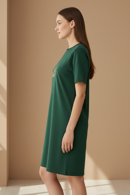 Woman wearing a dark green t-shirt dress against a beige wall