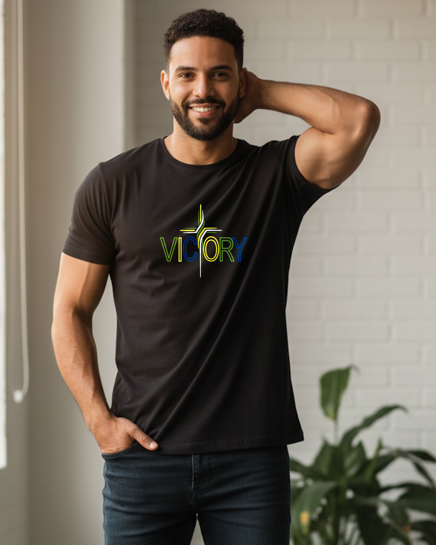 A man wearing a black short-sleeve t-shirt with a colorful 'VICTORY' graphic on the chest, standing indoors.
