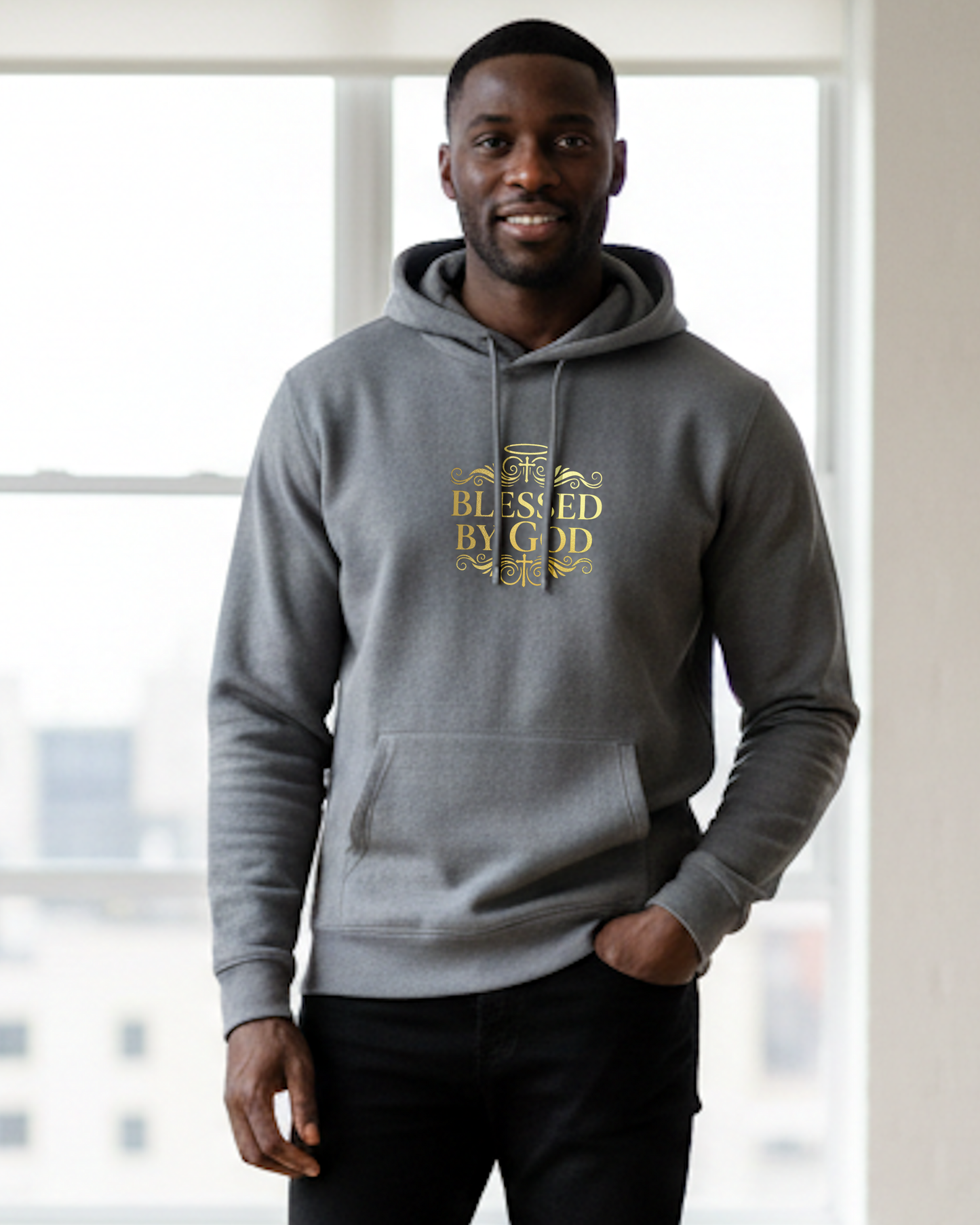 Man wearing a grey hoodie with 'Blessed by God' gold text, standing indoors.