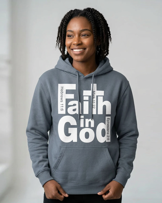 A smiling woman with braided hair wearing a slate gray hoodie with a large white graphic reading 'Faith in God' and Bible verse references, posed against a light gray background.
