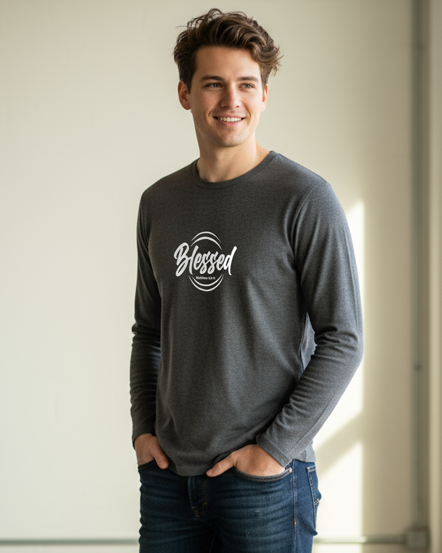 Man wearing a gray long-sleeve shirt with 'Blessed' white print, standing against a neutral background.
