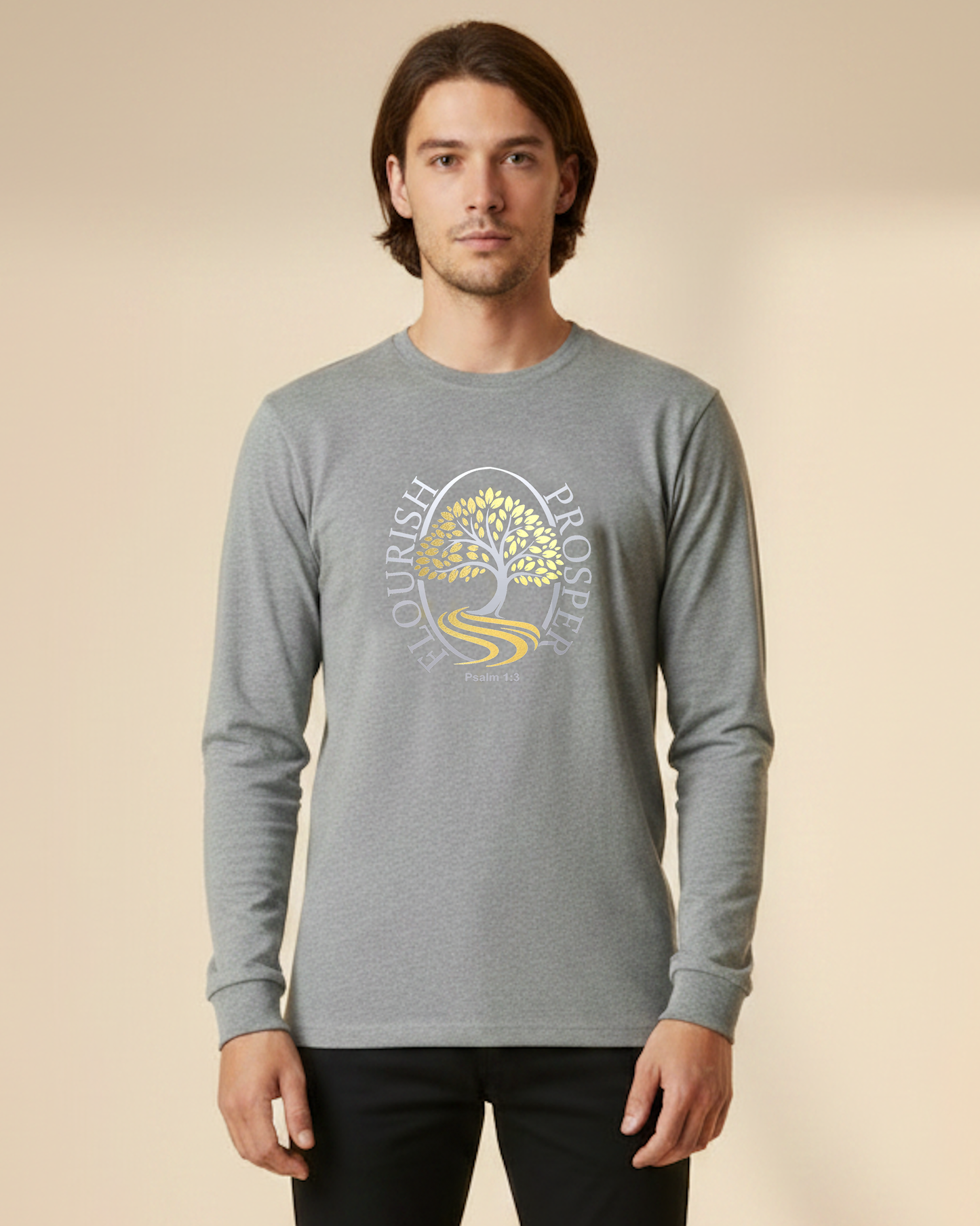 Man wearing a grey long sleeve t-shirt with a gold and silver logo of a tree near a river with the text Flourish Prosper on the front against a beige background.