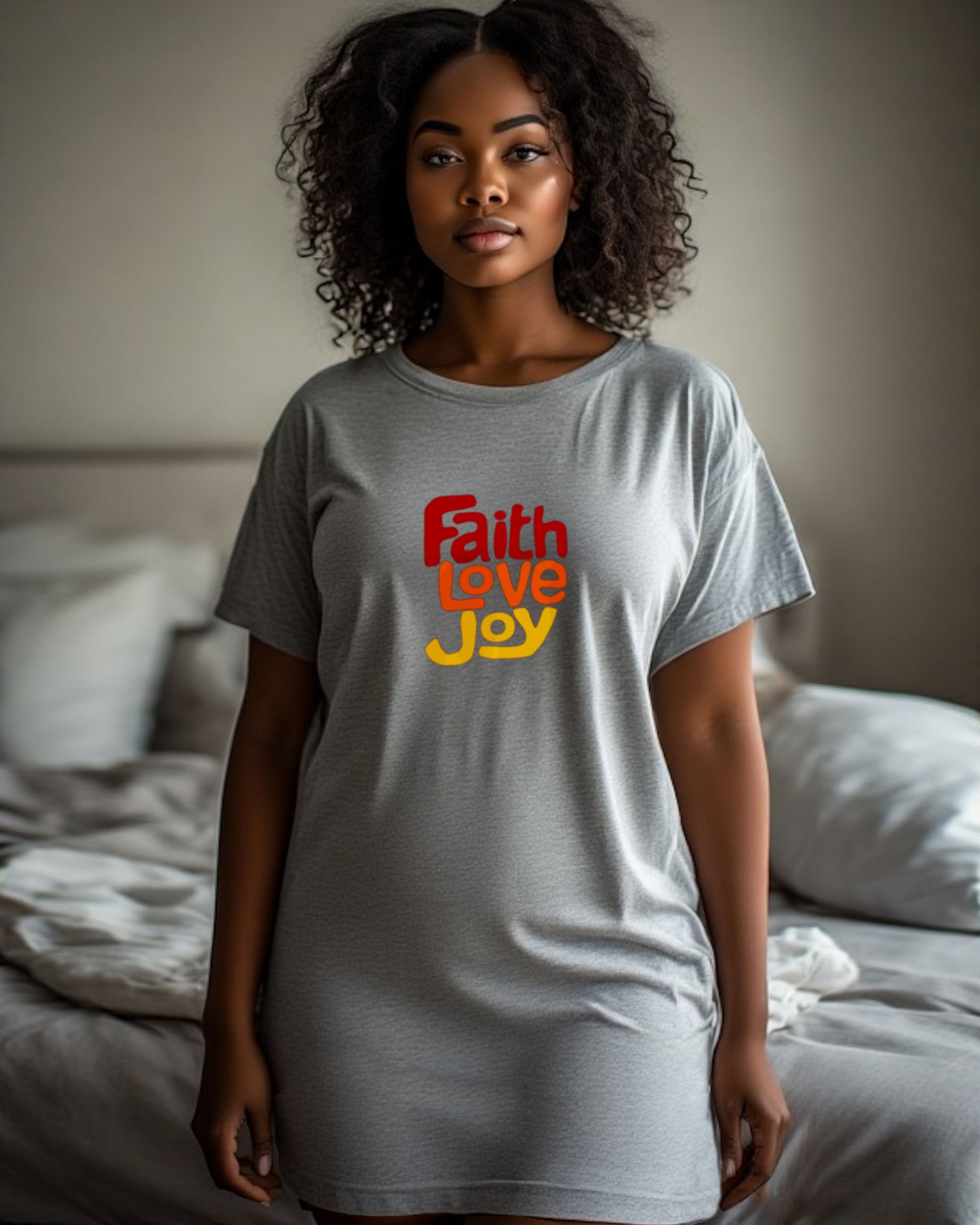 Woman wearing a grey nightdress with 'Faith Love Joy' text in red, orange, and yellow in a bedroom.