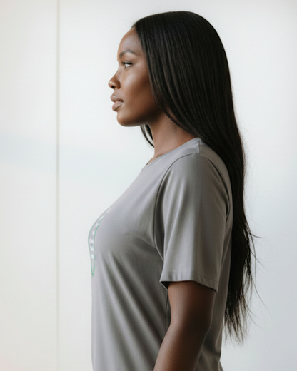 Woman with long black hair wearing a light gray t-shirt against a white background