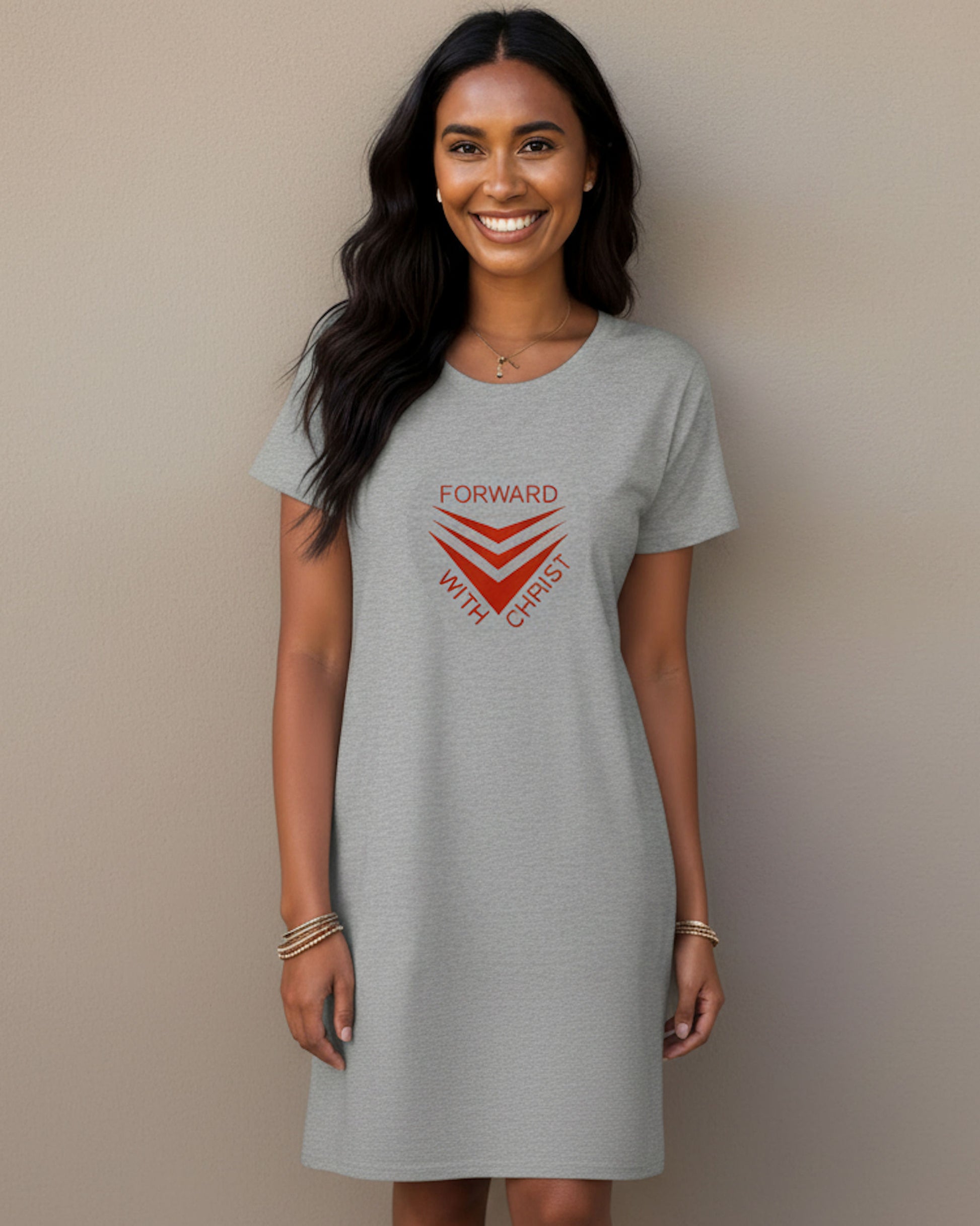 A woman wearing a light gray heather crewneck t-shirt dress with a red graphic on the front that reads 'FORWARD WITH CHRIST' and features red chevron stripes, set against a plain beige background.