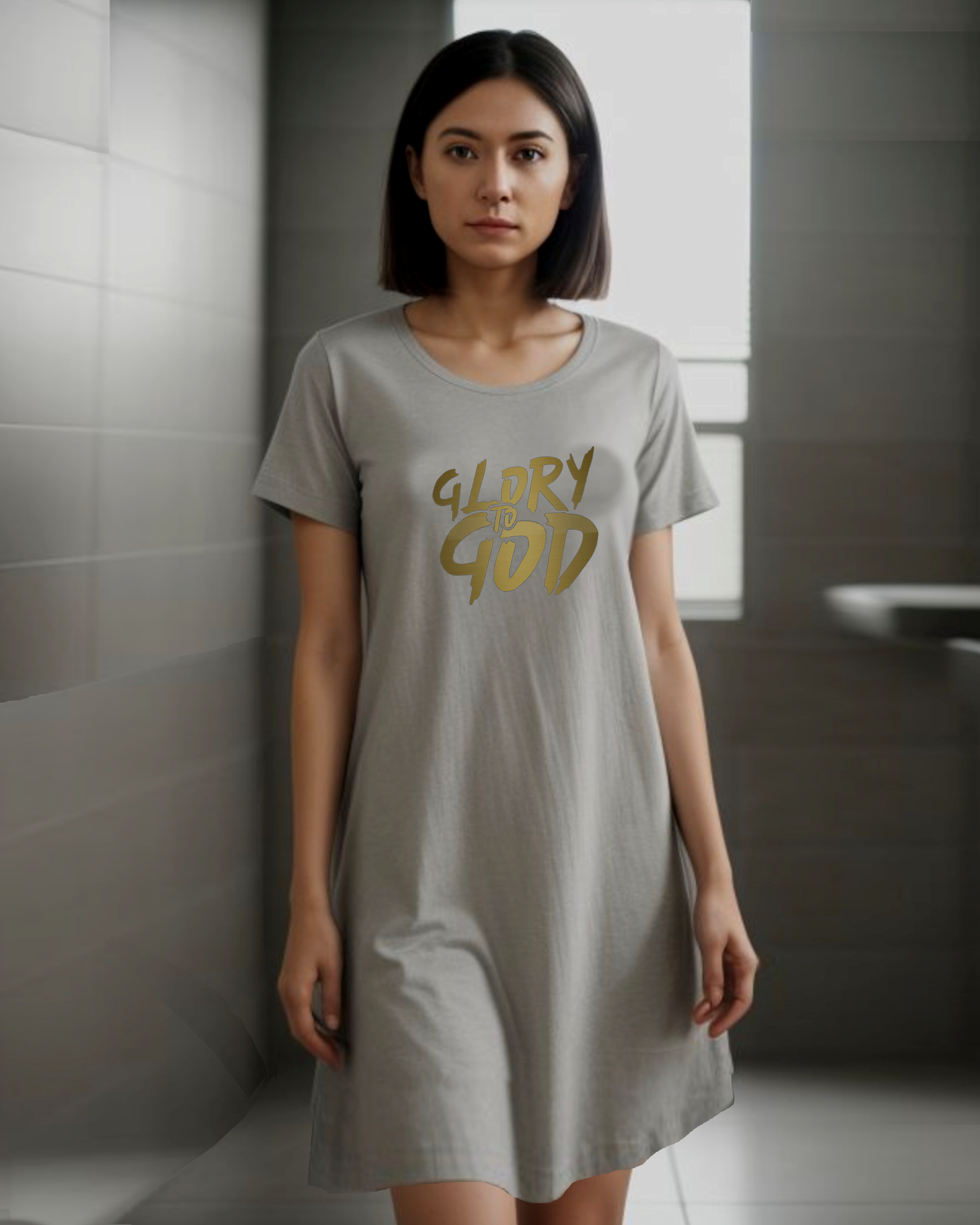 A woman in a bathroom wearing a grey cotton Heavenly Dreamwear nightdress with a gold "Glory to God" logo printed on the front.