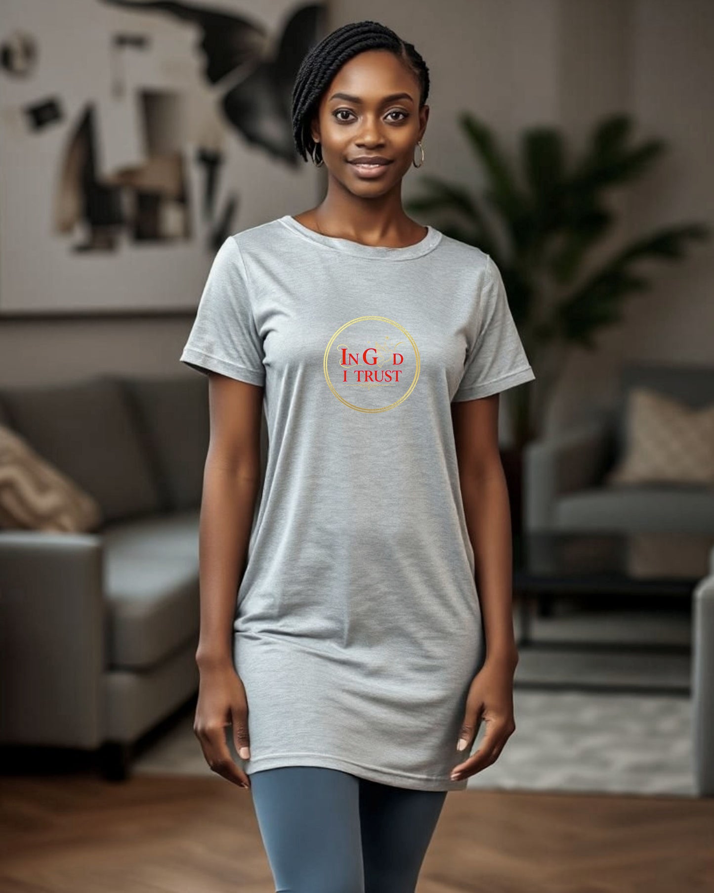 Woman wearing a grey t-shirt dress with a logo bearing text, "In God I trust" in a living room setting