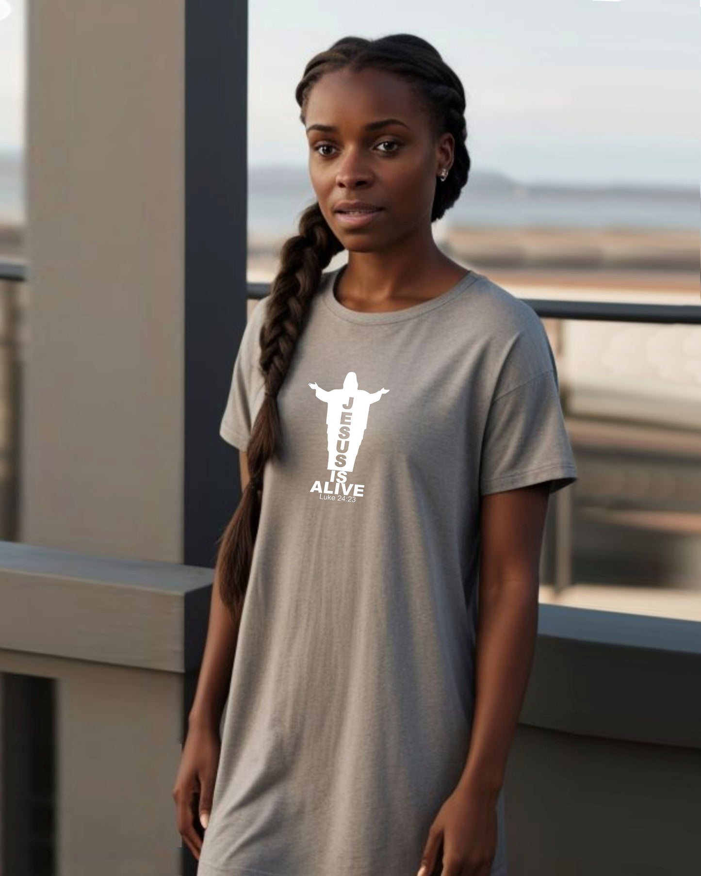 Woman on a balcony wearing a grey t-shirt dress with a white Jesus silhouette graphic and text.
