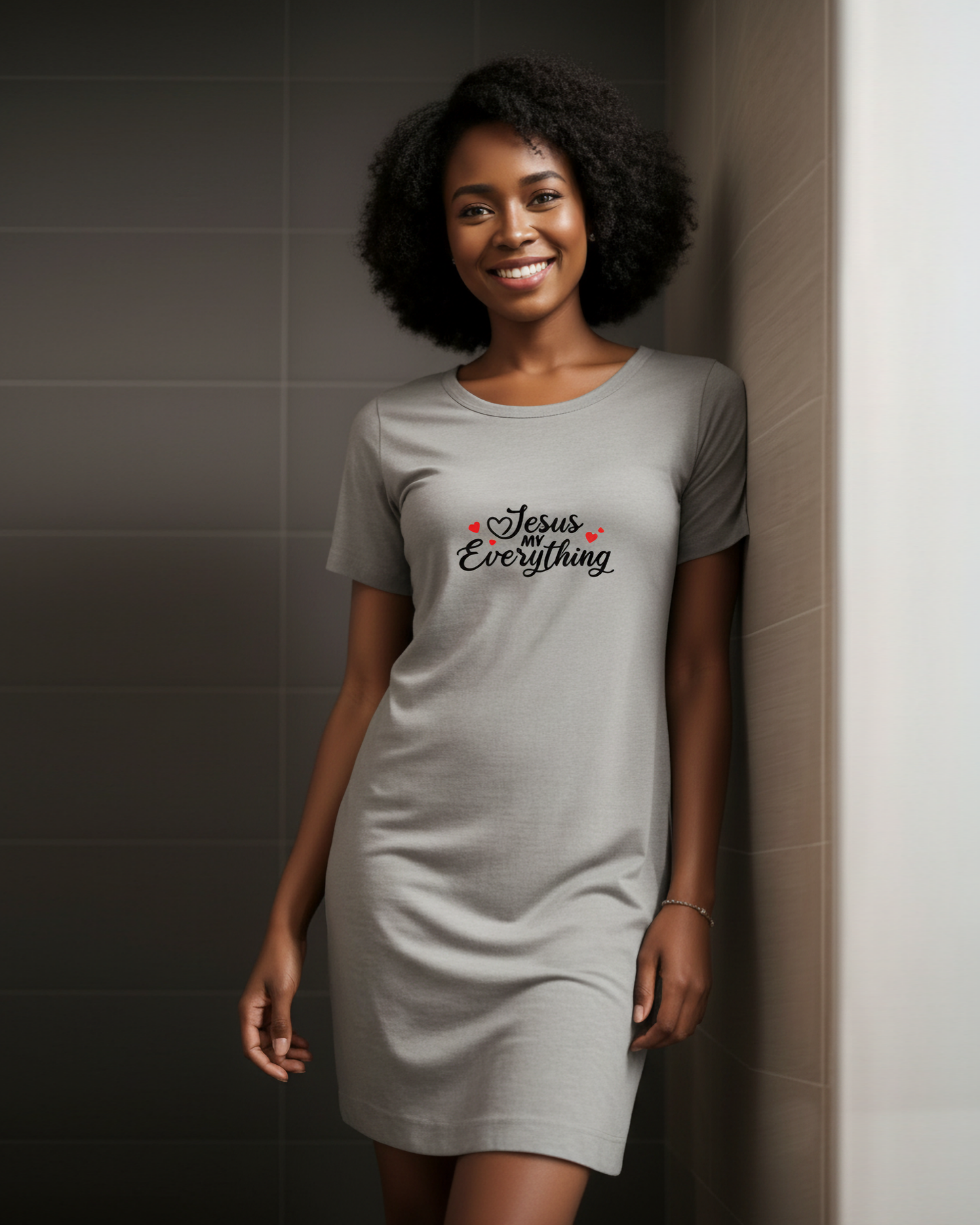 Woman wearing a gray dress with 'Jesus Loves Everything' text against a tiled wall.
