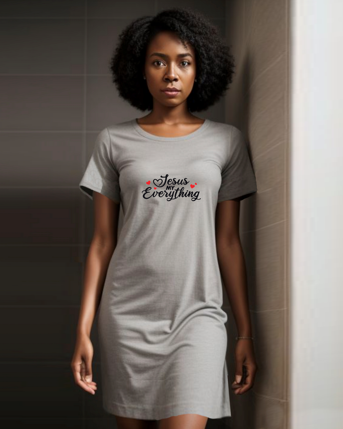 Woman wearing a grey Heavenly Dreamwear t-shirt dress in a tiled bathroom with a black text logo "Jesus MY Everything" with 4 red hearts printed on the dress.