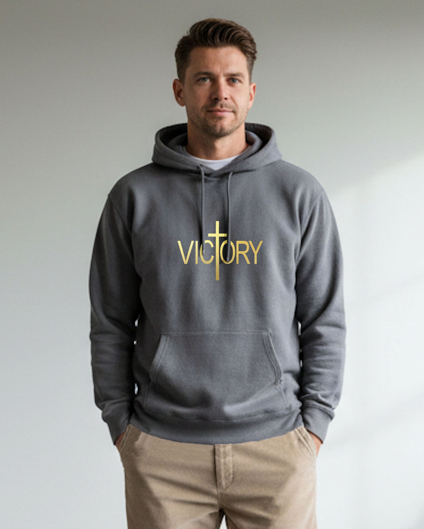 Man wearing a grey hoodie with 'VICTORY' printed on it in gold text against a neutral background
