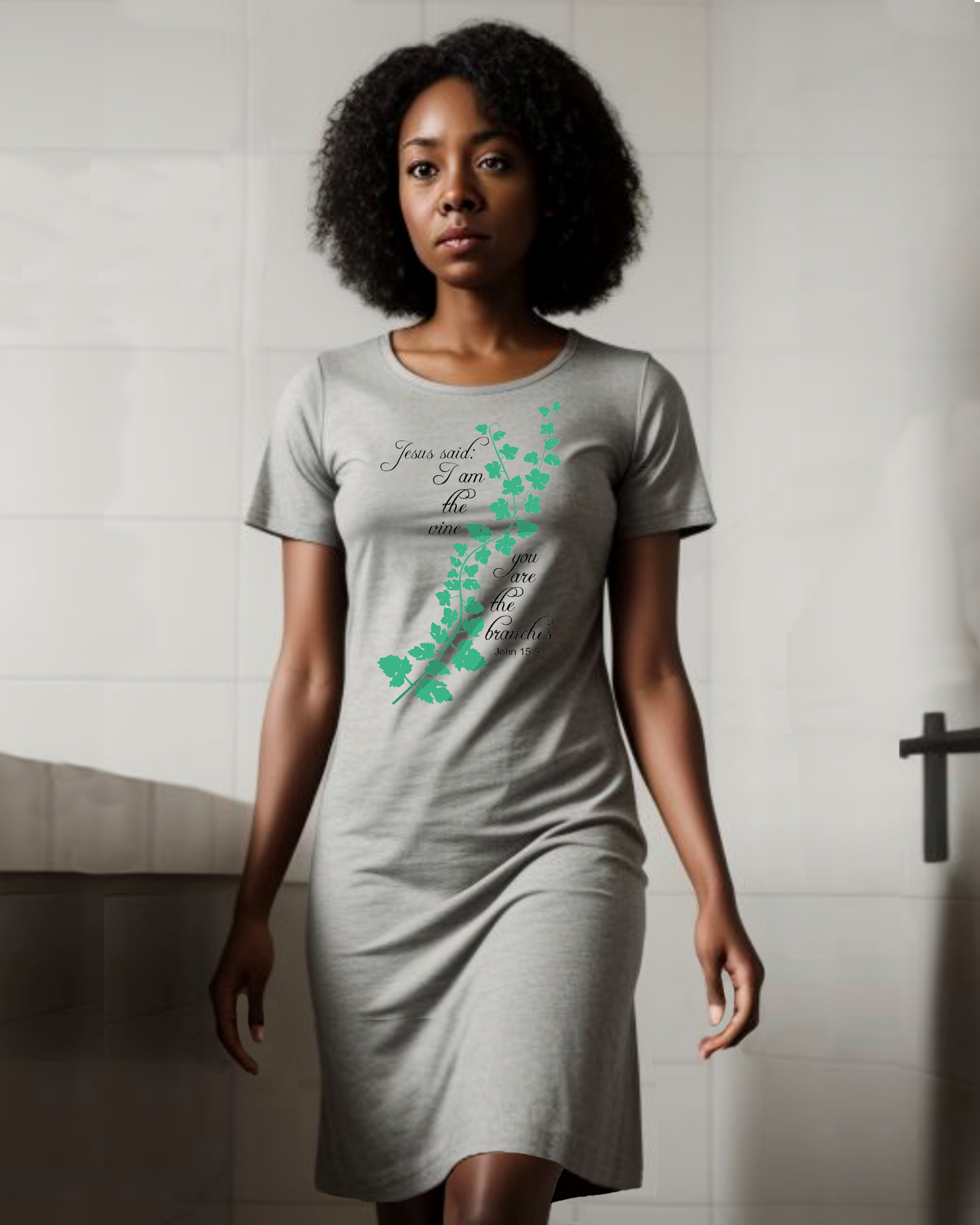 A woman wearing a grey t-shirt dress with an elaborate green vine branch with the text, "Jesus said: I am the vine you are the branches" printed in black text on either side.
