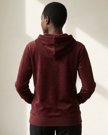 Woman wearing a maroon hoodieviewed from the rear on a neutral background