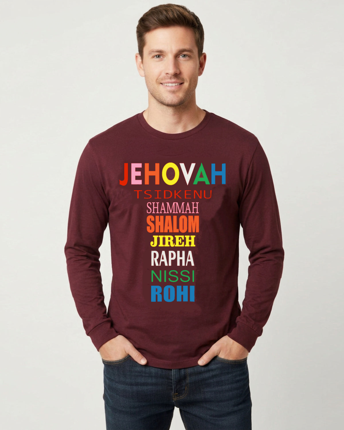 A man wearing a maroon long-sleeve t-shirt with a colorful Hebrew text graphic on the chest, paired with dark blue jeans, against a light gray background.