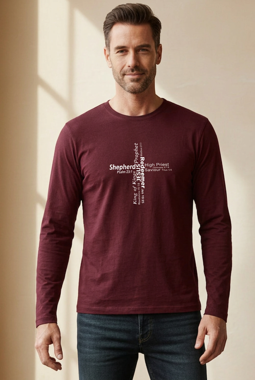 A man wearing a maroon long-sleeve crewneck t-shirt against a beige wall. The front of the shirt features a white typographic cross design with the various roles of Jesus.