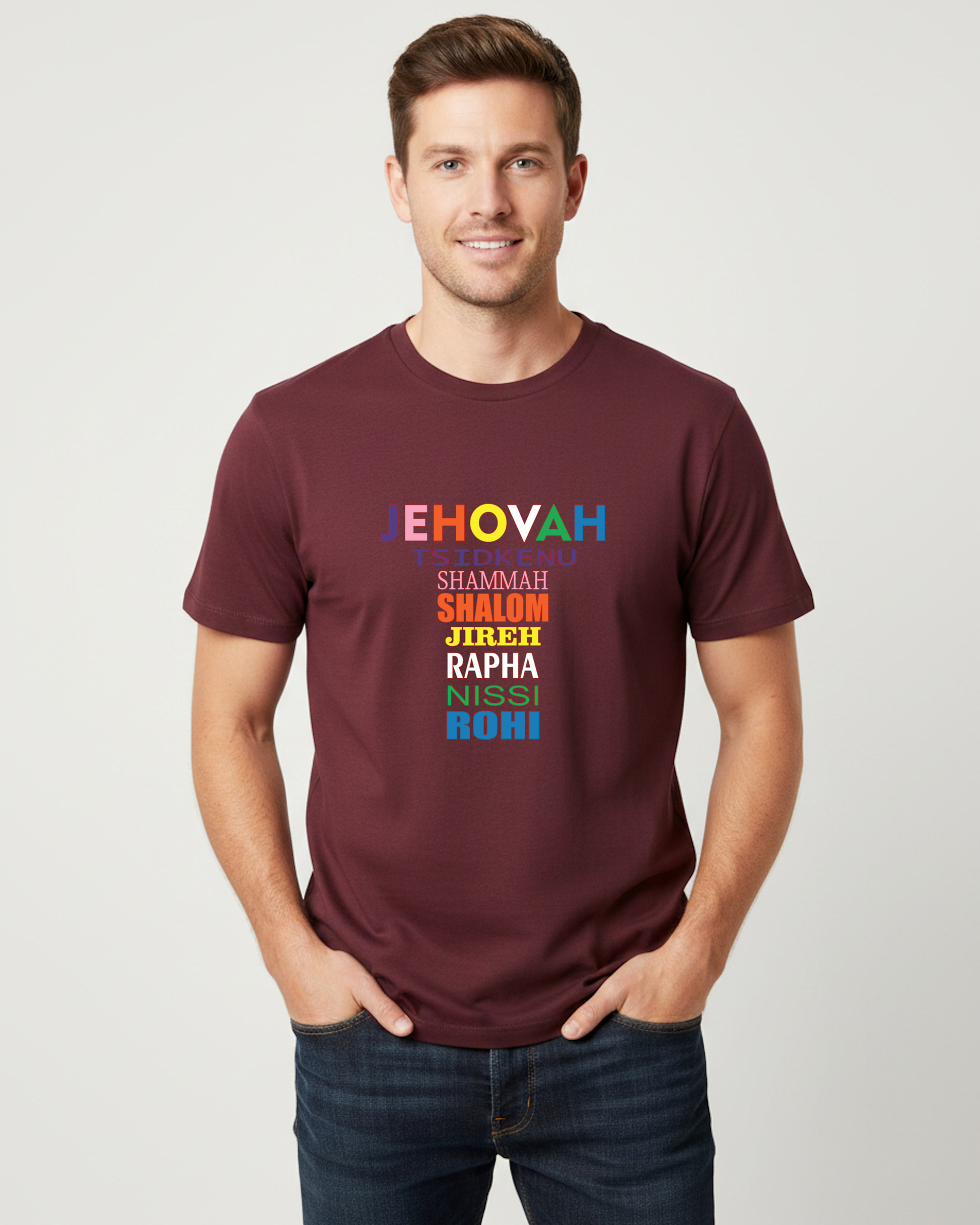 A man wearing a maroon crewneck t-shirt with a colorful text graphic on the chest, paired with dark blue jeans, standing against a light gray background.