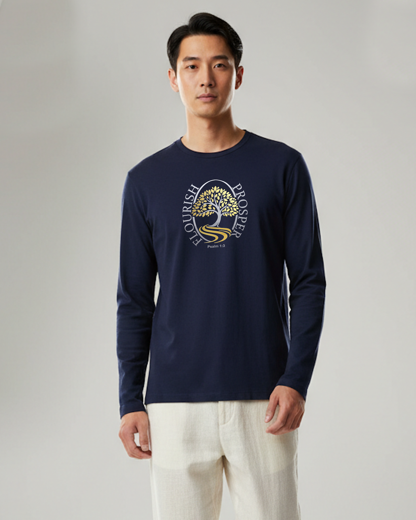 Man wearing a navy blue long sleeve t-shirt with a gold and silver logo of a tree near a river with the text Flourish Prosper on the front against a white background.