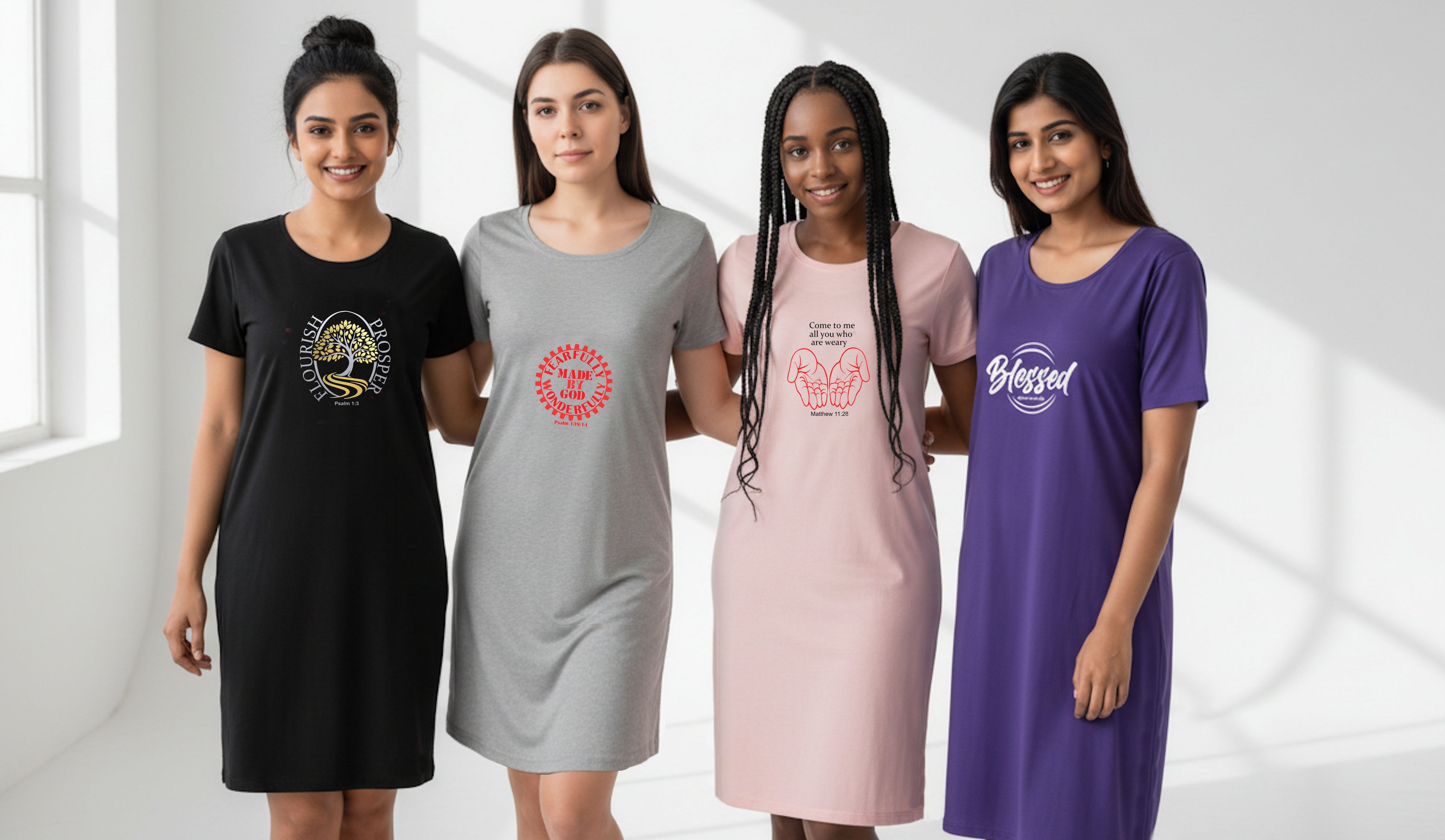 Four women standing side by side wearing matching oversized short-sleeve t-shirt dresses in black, gray, pink, and purple, each with a different colorful graphic print on the front, set against a bright white room background.